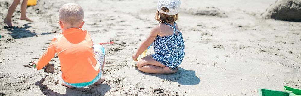 Toddlers playing at the beach in their swimsuits