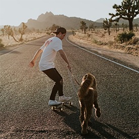Skateboarding with dog in California